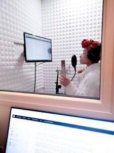 Ludmilla Andrushenko en studio d'enregistrement pour la création de son podcast, casque audio, micro, écran de texte et ambiance intimiste